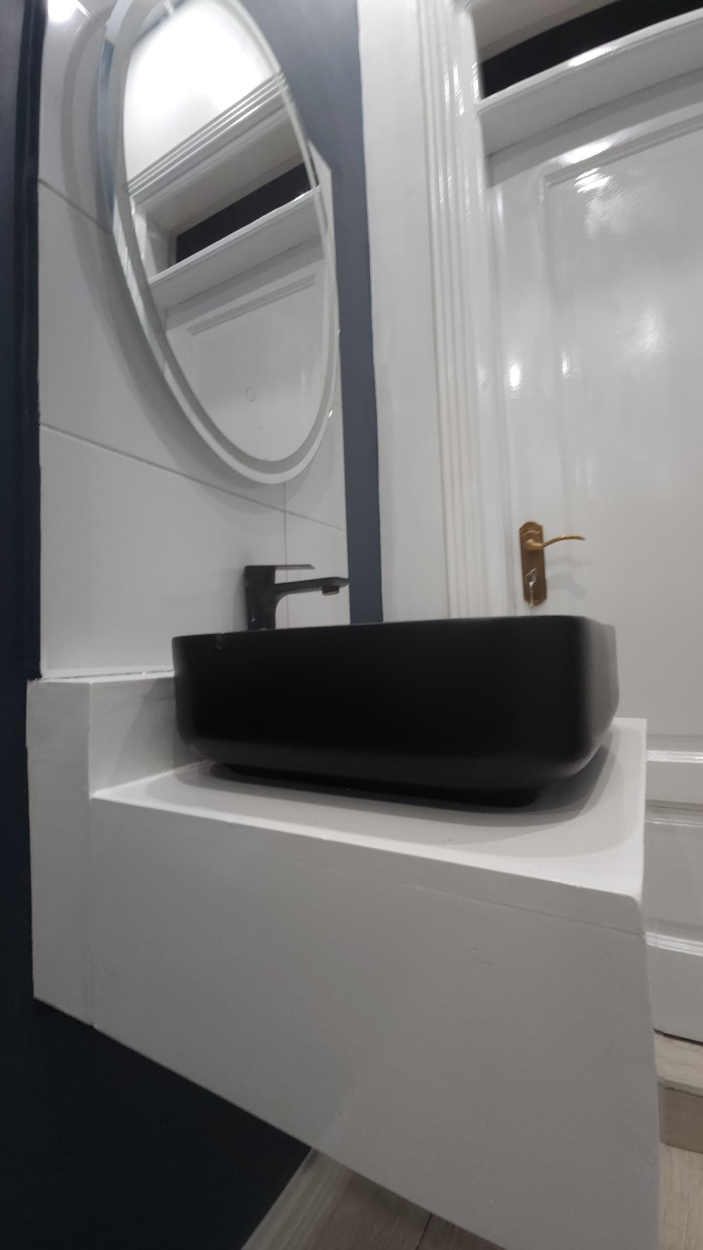 A modern bathroom with a white vanity, a black sink, and a mirror.