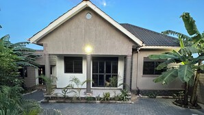 A two-story house with a tiled driveway and a small garden area. - Luxury home,  located in a quiet and calm area, Home away from home. (Entebbe)