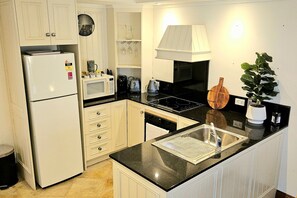 Fully equipped kitchen with refrigerator, microwave, and stove, sink, and contemporary faucet.