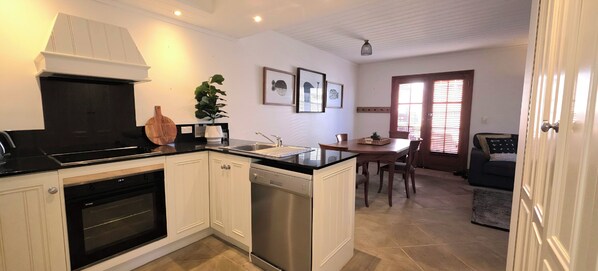 Efficient kitchen and dining area with modern appliances, wooden table, and potted plant.