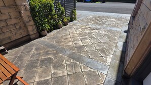 A stone-tiled patio with a wooden bench and potted plants. - Sandstone Suites (Port Fairy)