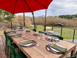 A wooden deck with a table set for a meal, green chairs, and a red umbrella. - Vineyard Estate -- Hot Tub, Fire Pit — Sleeps 8 (Sebastopol)