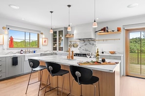 Uma cozinha moderna com uma ilha grande, banquetas e vista para o exterior.