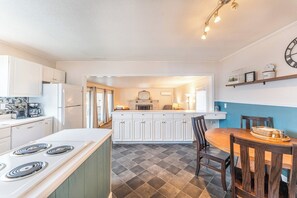 A modern kitchen with white cabinets, a central island, and a dining area with a wooden table and chairs.
