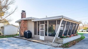 Une maison de plain-pied avec un porche couvert, une cheminée en briques et un garage.