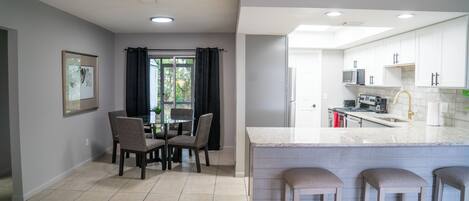 A modern kitchen with white cabinets, a granite countertop, and a stainless steel sink.