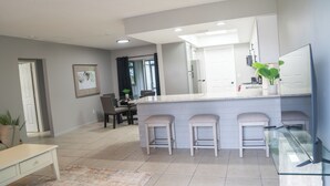 A modern kitchen with a central island, bar stools, and a dining area with chairs. - Cozy 2-bedroom hideaway with WiFi, AC the heart of Fort Myers (Fort Myers)