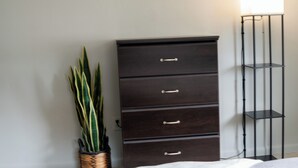 A bedroom with a bed, a dark wooden dresser, three round mirrors, a tall floor lamp, and a potted plant. - Cozy 2-bedroom hideaway with WiFi, AC the heart of Fort Myers (Fort Myers)