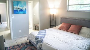 A bedroom with a bed, a nightstand, a lamp, and a painting on the wall. - Cozy 2-bedroom hideaway with WiFi, AC the heart of Fort Myers (Fort Myers)