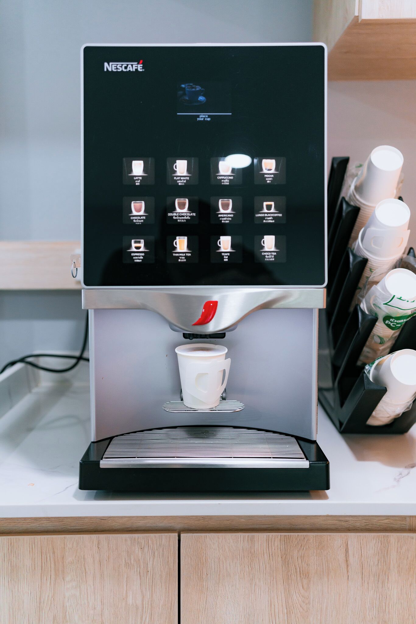 Una máquina de café Nescafé con pantalla táctil y un portavasos.