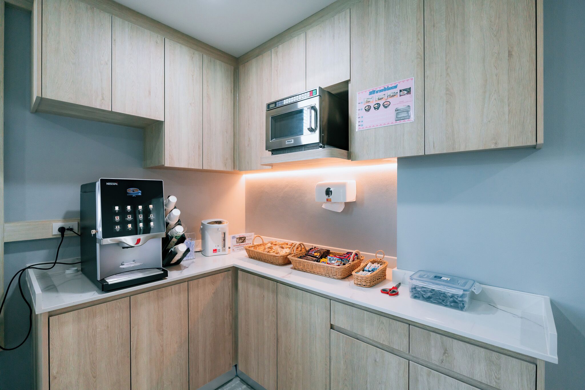 Una kitchenette con cafetera, microondas y cestas de aperitivos.
