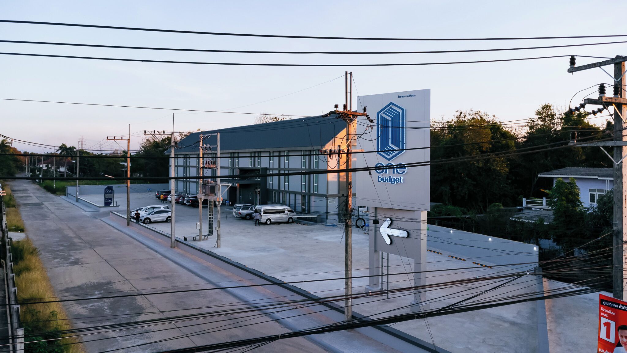 A building with a large sign reading "one budget" and a parking lot with several cars.