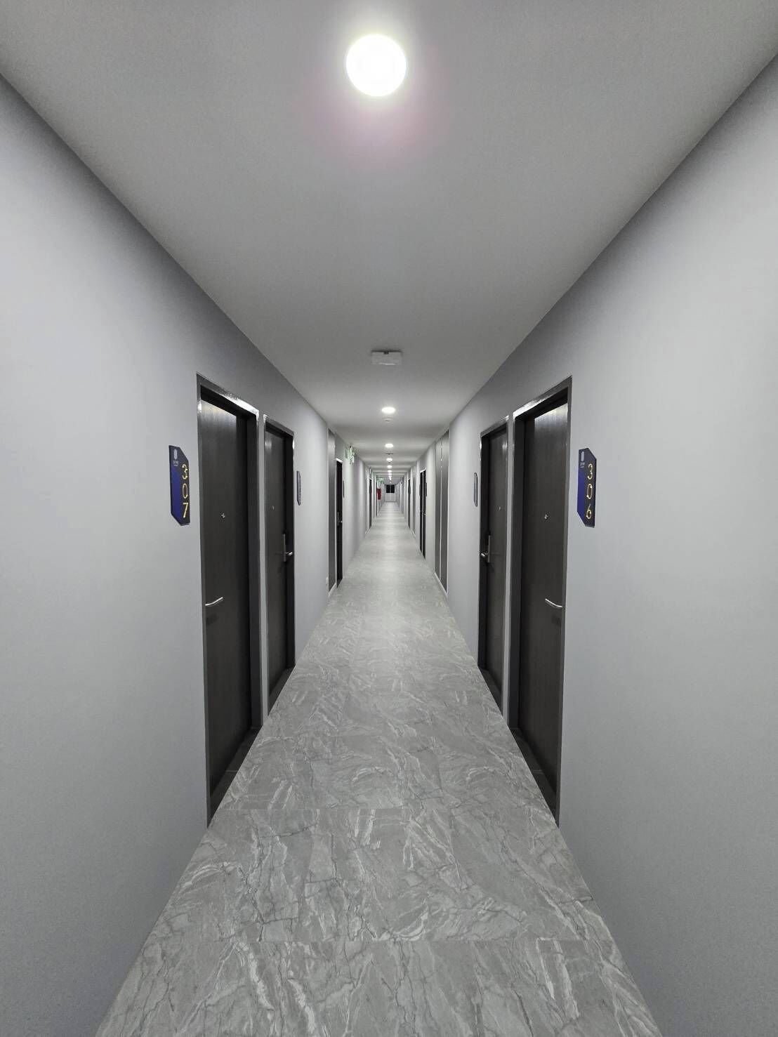 A long, narrow hallway with doors on both sides, each marked with a number.
