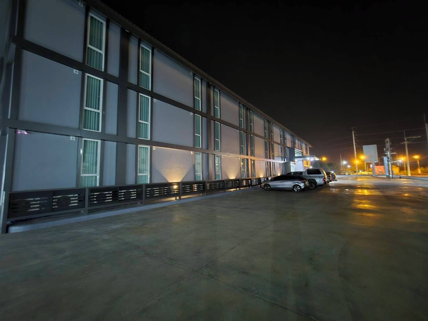 A modern building with large windows and a parking area.