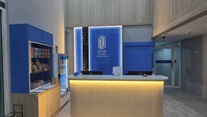 Een receptiebalie met een blauw en wit logo, een automaat en een display voor snacks.