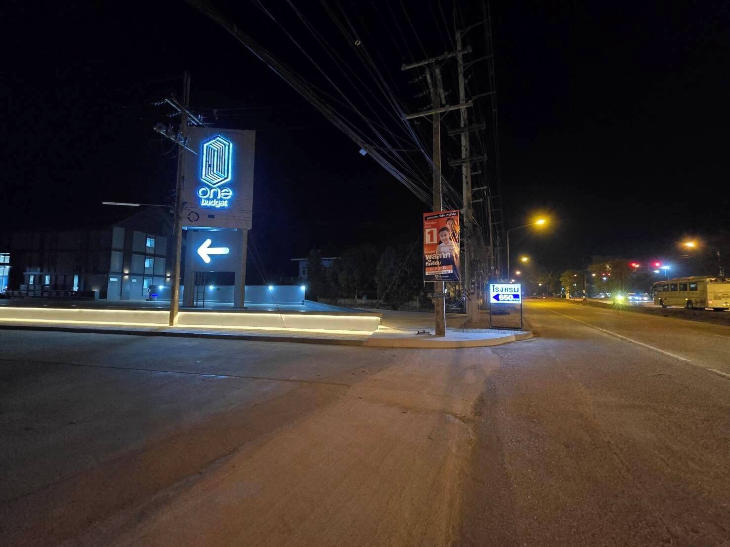 A night-time street view with a building featuring a 'One Budget' sign and a directional arrow.