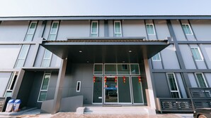 Een modern gebouw met een ruime ingang, veel ramen en een overdekte gang.