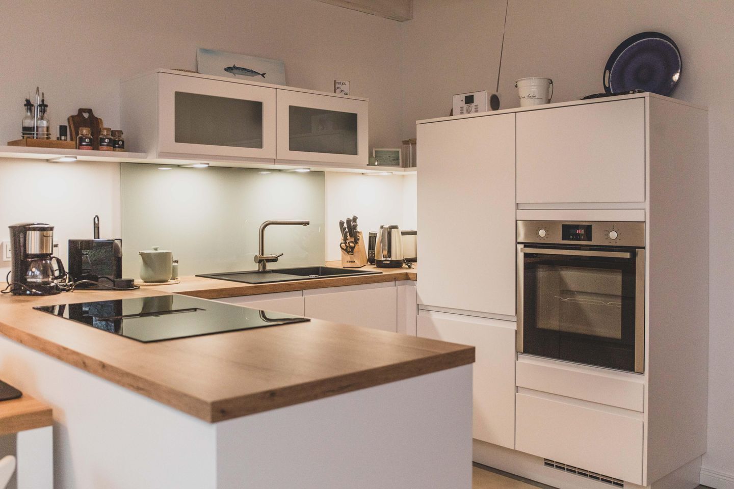 Una cocina moderna con horno integrado, un lavamanos y una cafetera.
