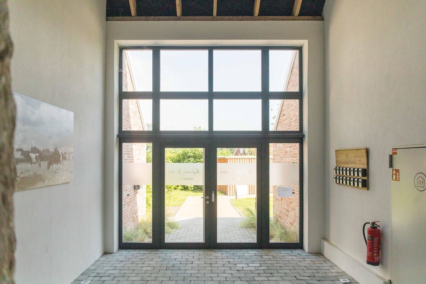 A room with a large window, a fire extinguisher, and a wall-mounted sign.