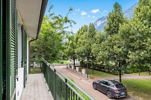 Un balcon donnant sur une route, des arbres et des montagnes.