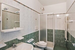 A bathroom with a sink, toilet, and shower area.
