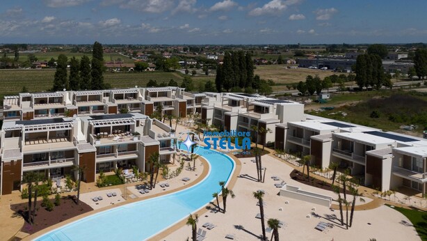 A resort with a swimming pool, sun loungers, and a view of the surrounding landscape.