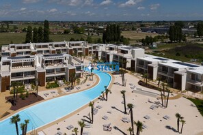 A resort with a swimming pool, sun loungers, and a view of the surrounding landscape. - *Wave Island Resort Attic* [ pool & free park ] (Lido di Jesolo)