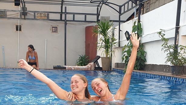 Una piscina con dos personas nadando, una levantando el brazo.