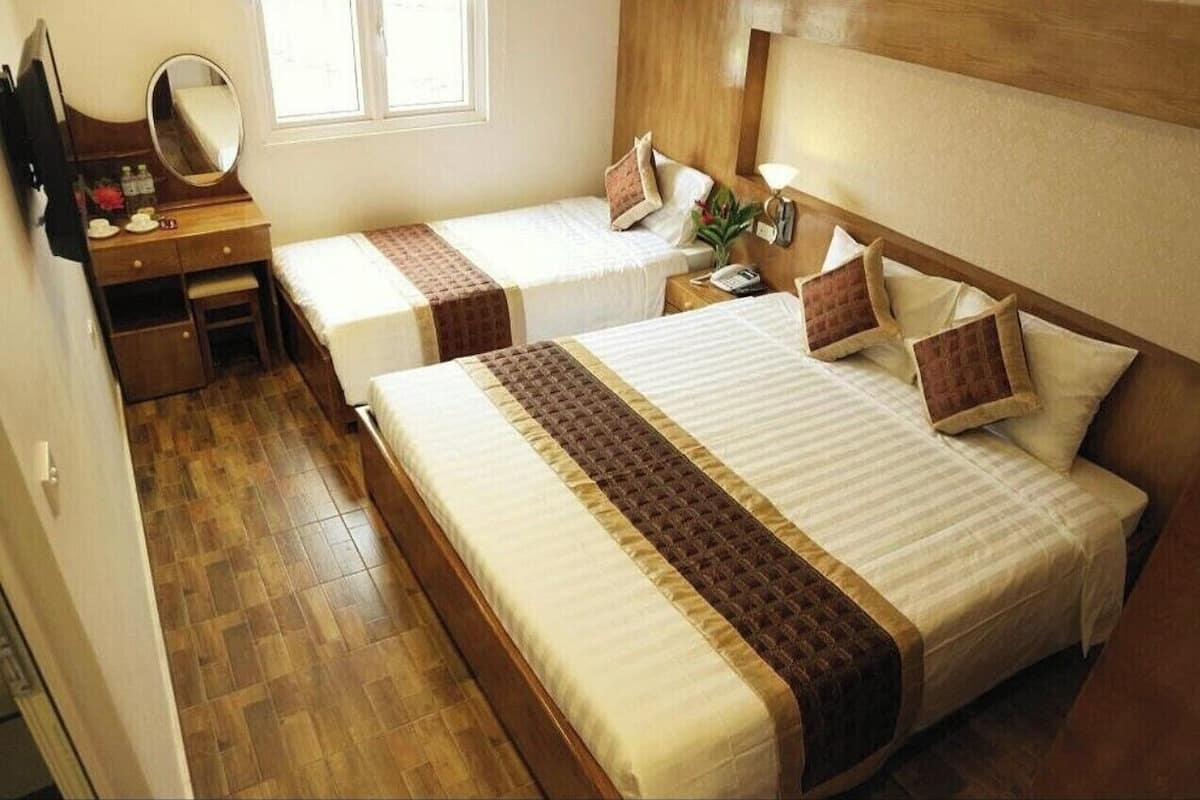 A hotel room with two beds, a wooden dresser, a mirror, and a window.