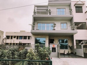 Un edificio residencial de varios pisos con balcones, ventanas amplias y una entrada con portón.