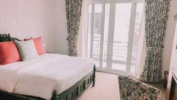 A bedroom with a bed, floral curtains, and a view of the outside.