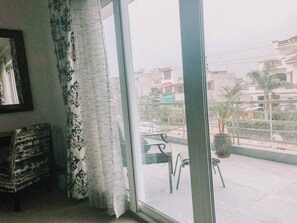 Una habitación con un ventanal grande, una silla y una mesa en el exterior.