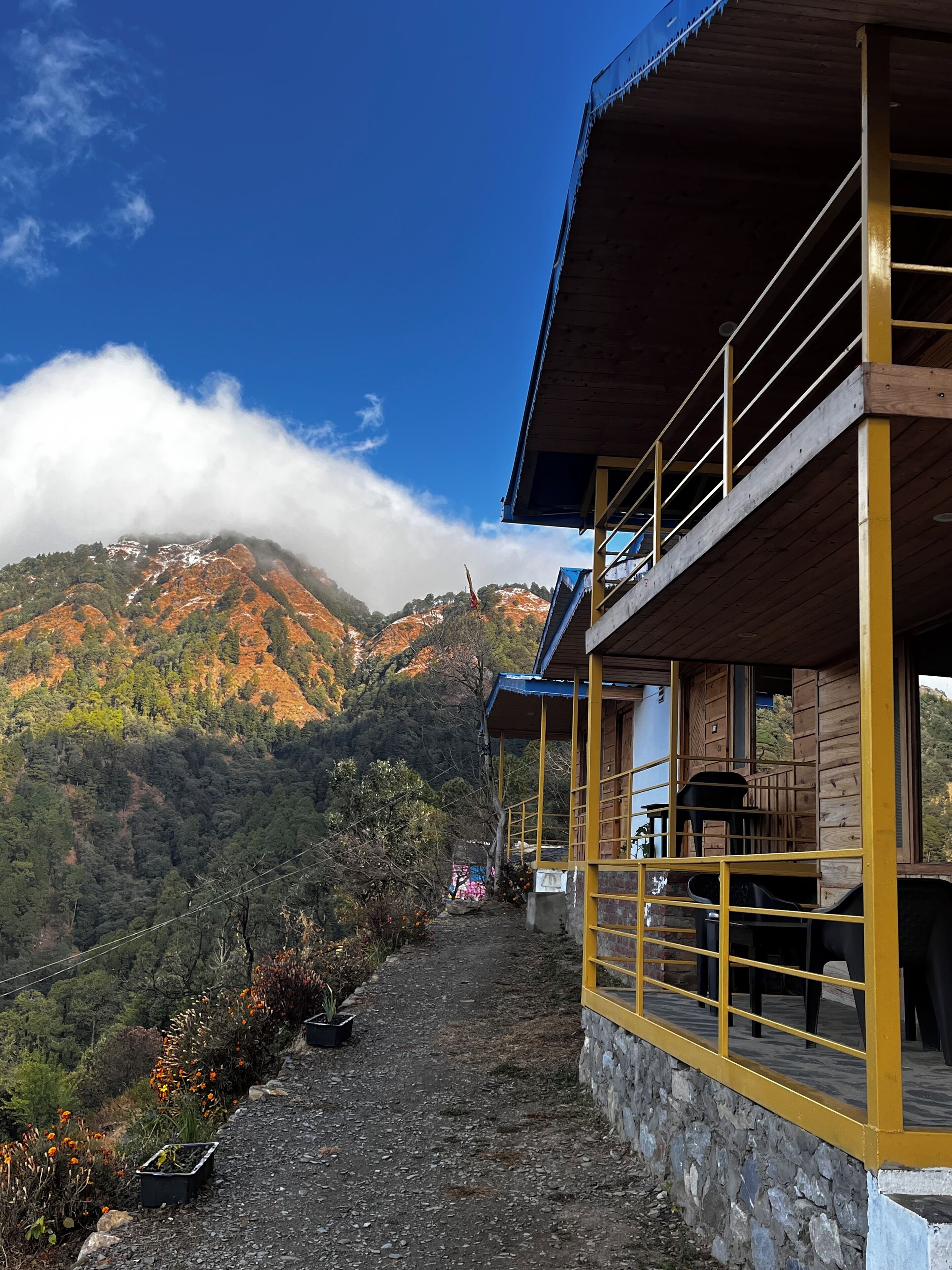 A two-story building with a balcony, surrounded by a mountainous landscape and a clear sky.