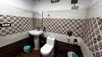 A bathroom with a sink, toilet, and a mirror. There is a patterned tile backsplash, a wooden floor, and a small trash bin.