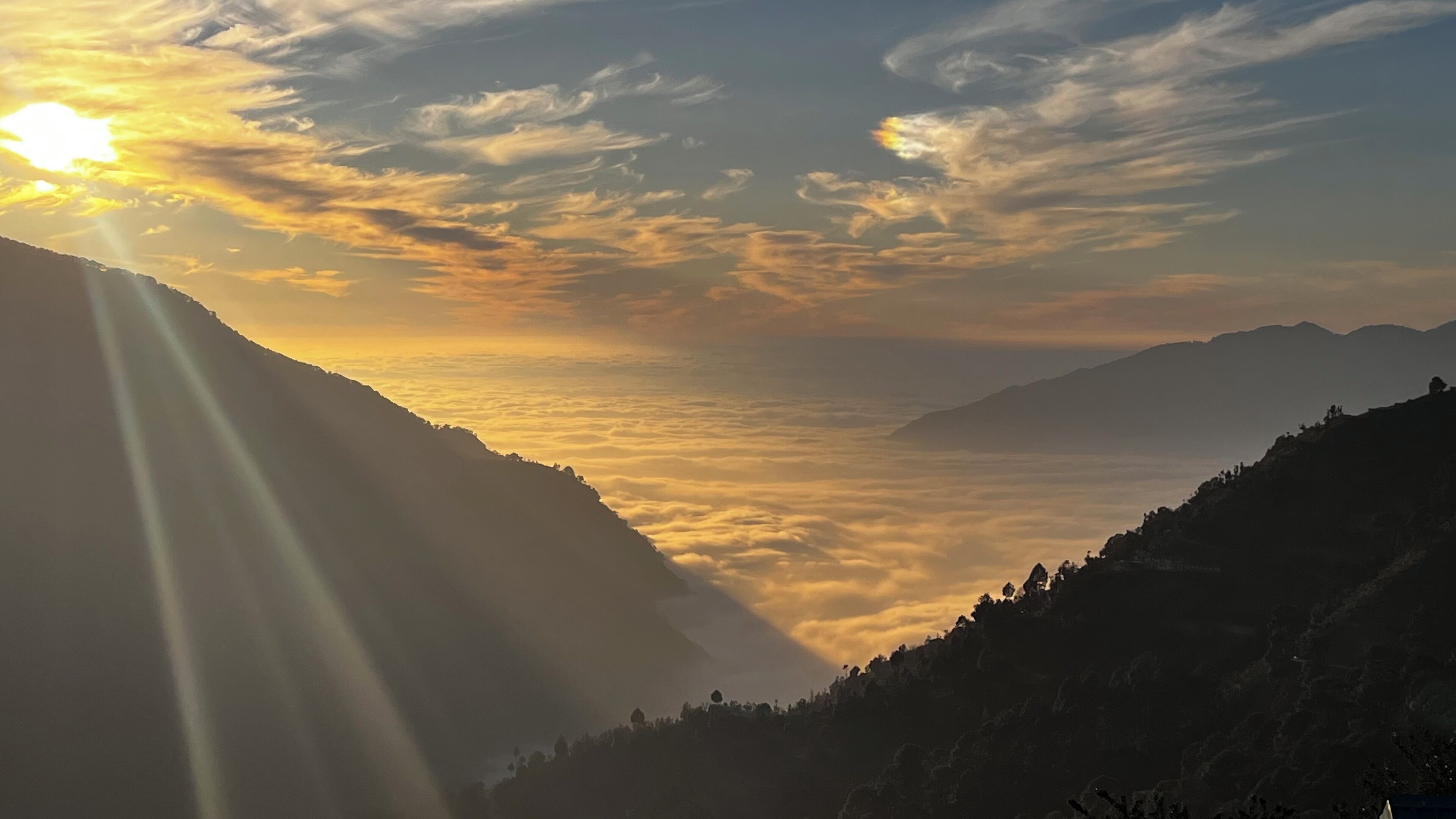 A mountainous landscape with a valley and a sunrise or sunset.