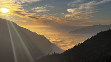 A mountainous landscape with a valley and a sunrise or sunset.