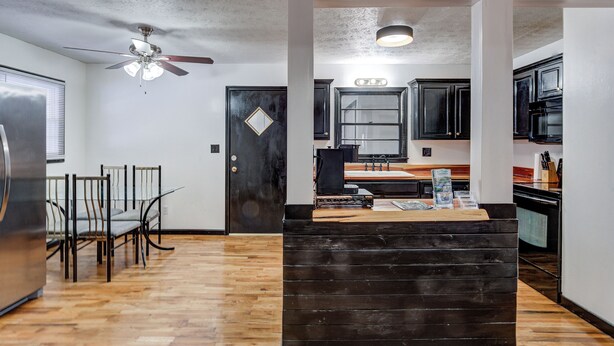 A modern kitchen with dark cabinets, a wooden island, and a ceiling fan. - Centralized Modern Home in Johnson City (Johnson City)