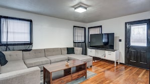 A living room with a sectional sofa, a TV, a wooden coffee table, and a door with a window. - Centralized Modern Home in Johnson City (Johnson City)
