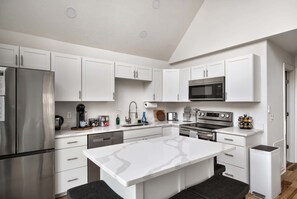Una cocina moderna con armarios blancos, electrodomésticos de acero inoxidable y una isla central.