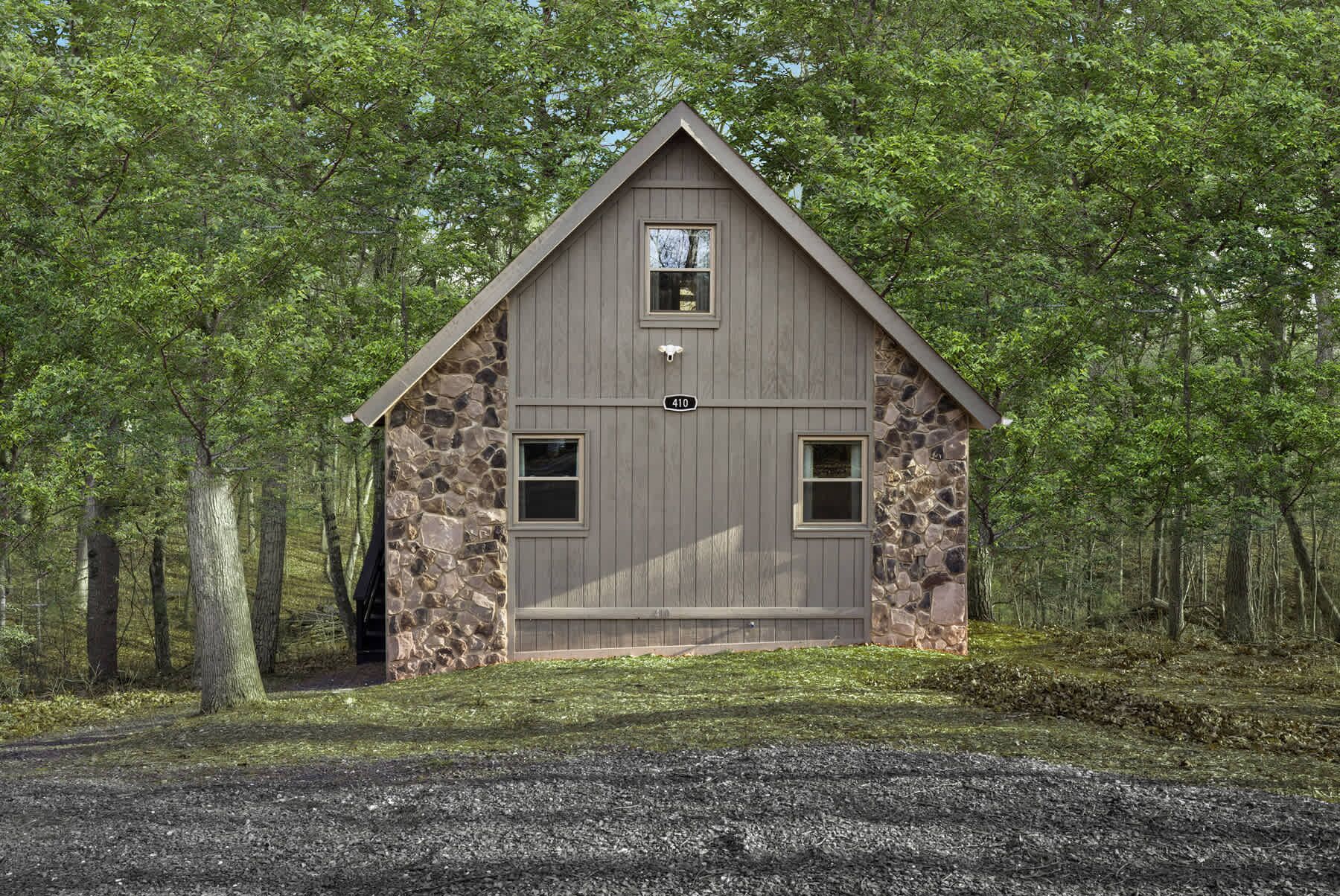 A cabin with a stone facade, a gabled roof, and a small porch.