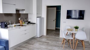 Una cocina moderna con armarios blancos, horno empotrado y comedor con mesa y sillas.