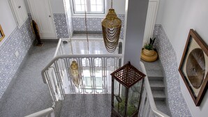Una escalera con cerramiento de vidrio, barandas blancas y lámparas colgantes decorativas.