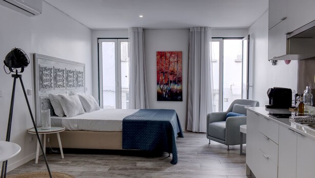 Un dormitorio moderno con cama, escritorio y silla. Hay un cuadro en la pared y una ventana con cortinas.