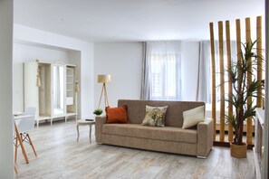 A living room with a beige sofa, a small side table, a lamp, a potted plant, and a wardrobe. - PB DLX Ilha - Palacete da Baixa (Faro)