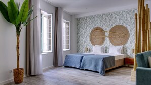 A bedroom with a bed, a potted plant, and a wall with a leaf pattern. - PB DLX Ilha - Palacete da Baixa (Faro)