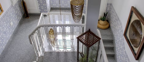 Een trap met glazen omheining, witte leuningen en decoratieve hanglampen.