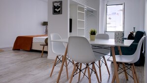 Une pièce moderne et bien éclairée, avec une table à manger, des chaises blanches et un canapé.