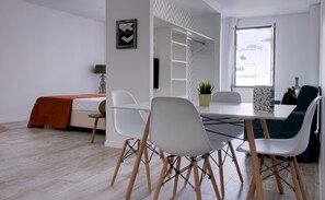 Una habitación moderna y luminosa con una mesa de comedor, sillas blancas y un sofá.