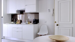 A modern kitchen with white cabinets, a stainless steel range hood, and a white chair. - PB STD Mar Timo - Palacete da Baixa (Faro)