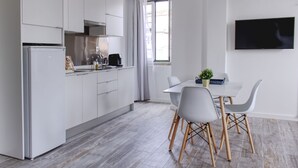 Una cocina moderna con armarios blancos, horno empotrado y una zona de comedor con mesa y sillas.